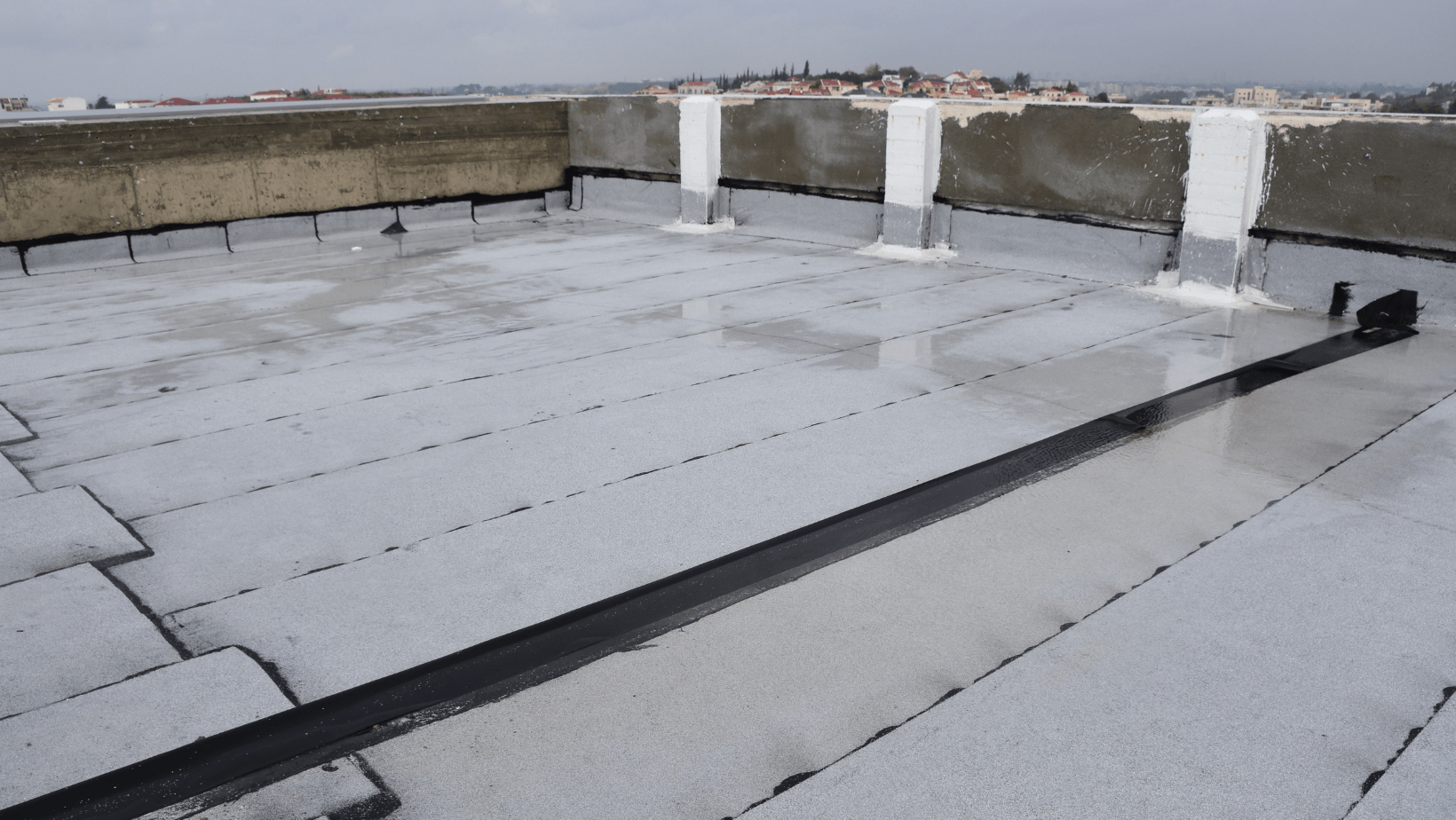 A flat roof featuring a prominent metal pipe extending upward from its surface.