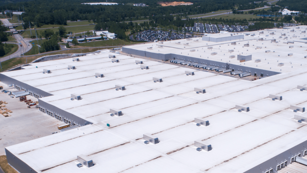 Aerial view of a large warehouse complex featuring multiple roofs, showcasing the expansive layout and structure.