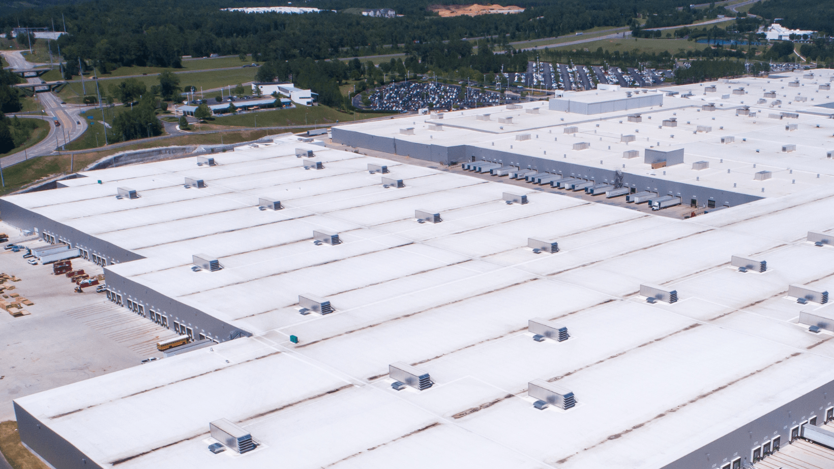 Aerial view of a large warehouse complex featuring multiple roofs, showcasing the expansive layout and structure.