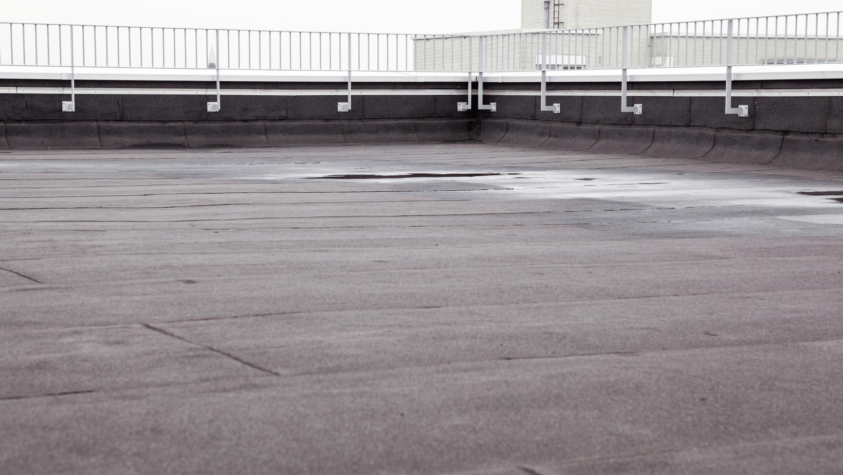 Industrial flat roof with visible seams and a surrounding metal railing.