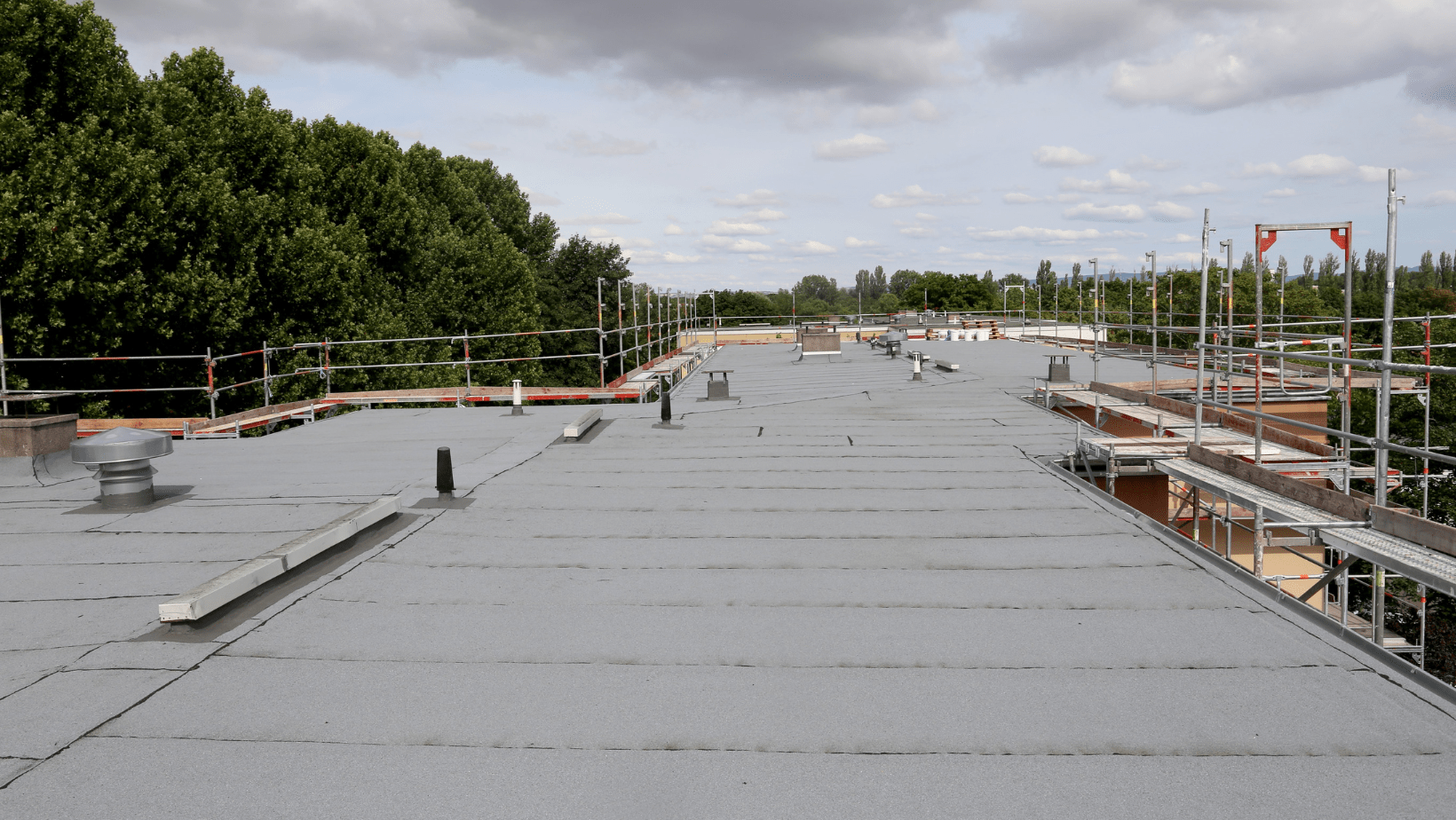 A roof under construction, featuring scaffolding and a newly installed metal roofing system.