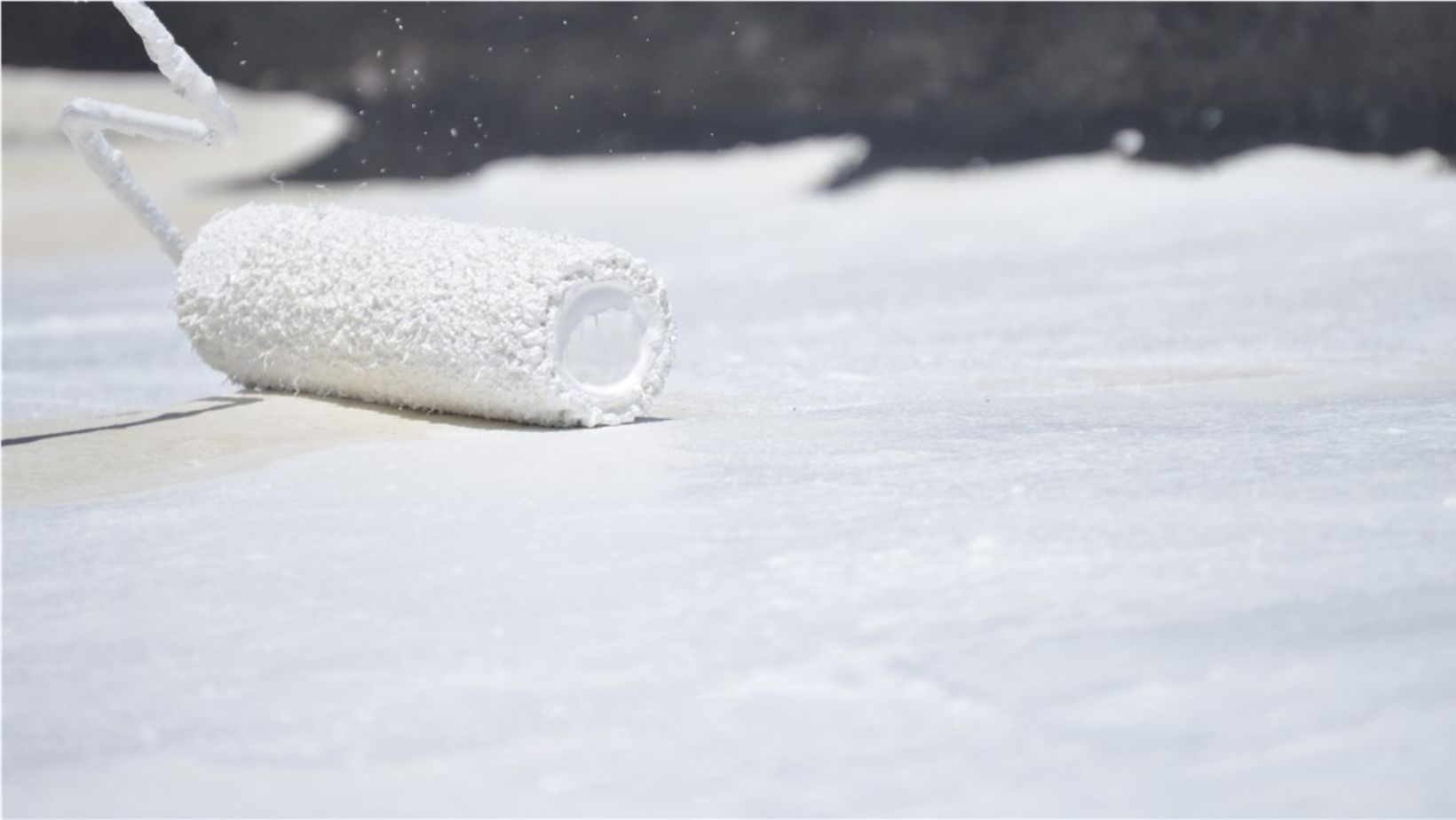 A white paint roller lying on the ground