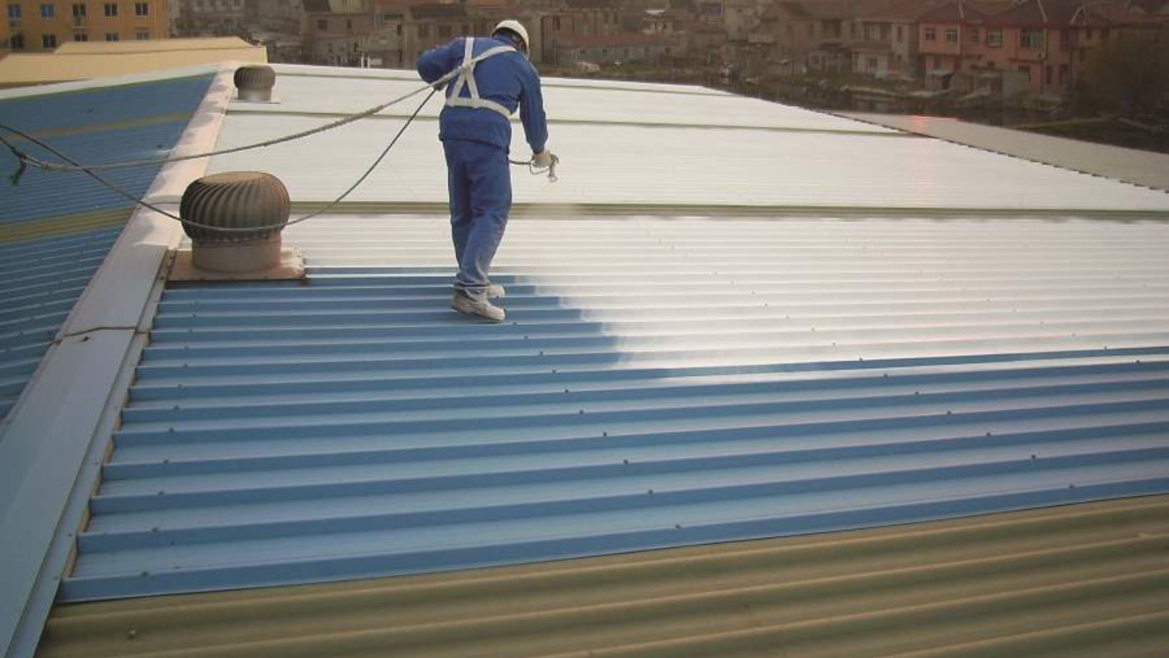 A man sprays white paint onto a roof