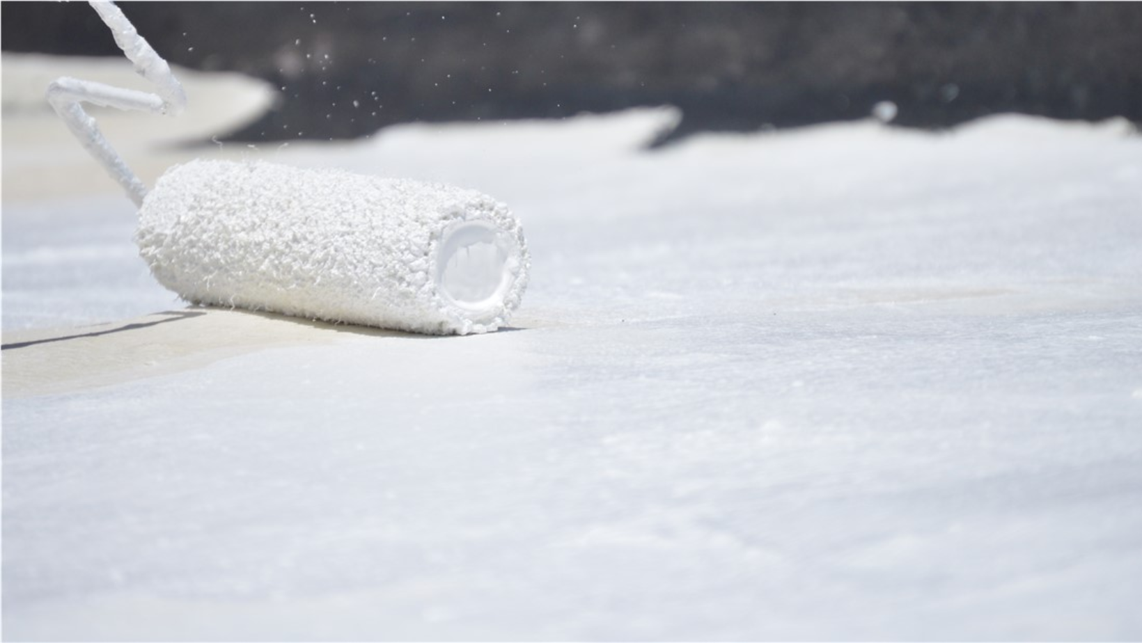 A white paint roller resting on the ground