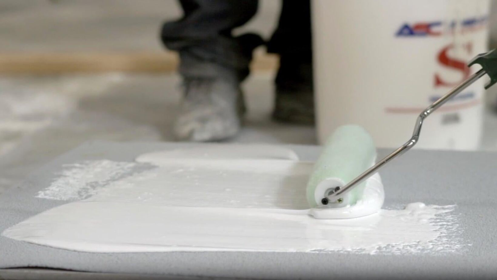  A person painting a roof with a paint roller