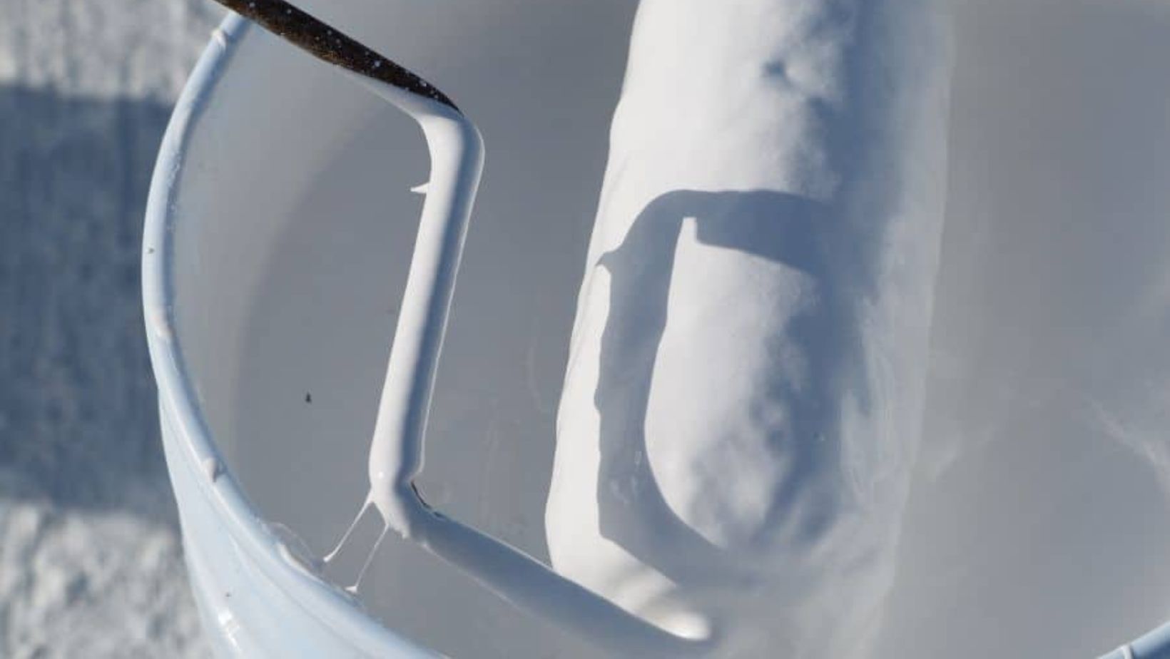 A person holds a bucket of white paint