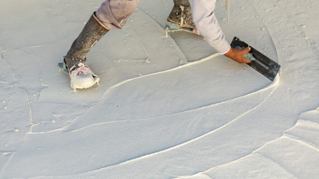 A person using a paint roller to apply paint to a white surface.