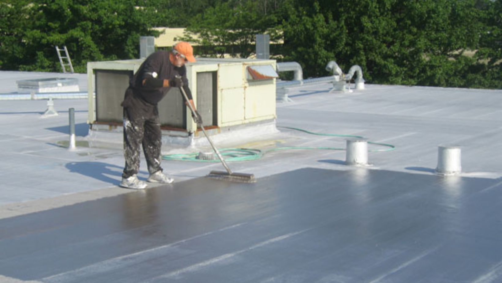 A man brushes the roof to prepare it for a new coating