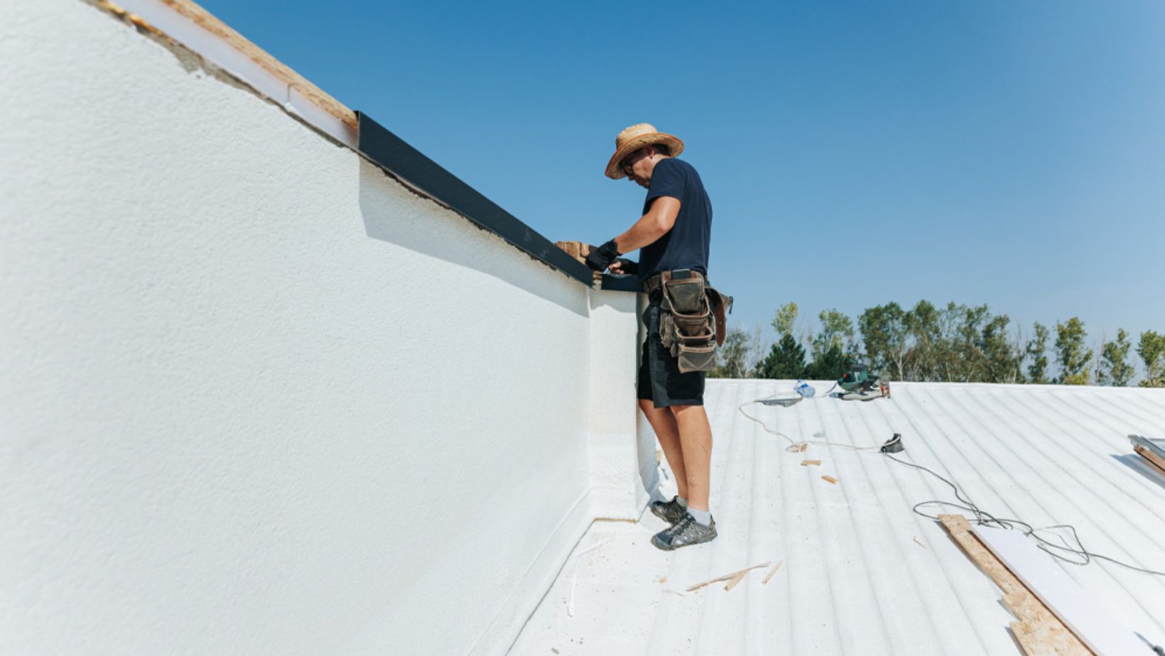 A man applying roof coating while working on a sloped roof