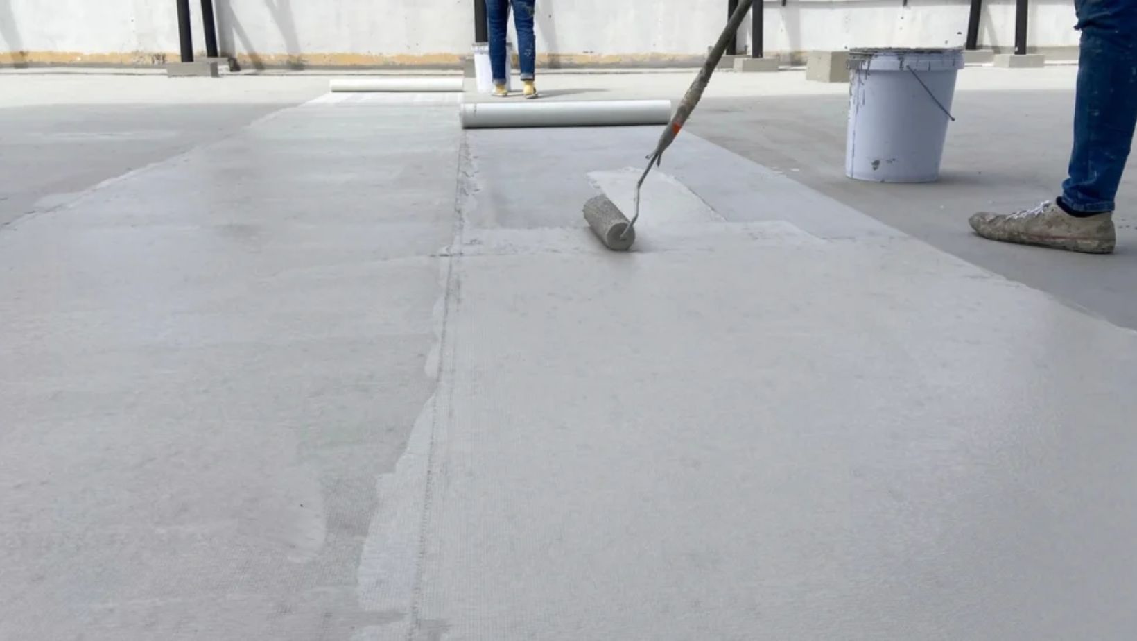 Individual painting a concrete floor with a roller